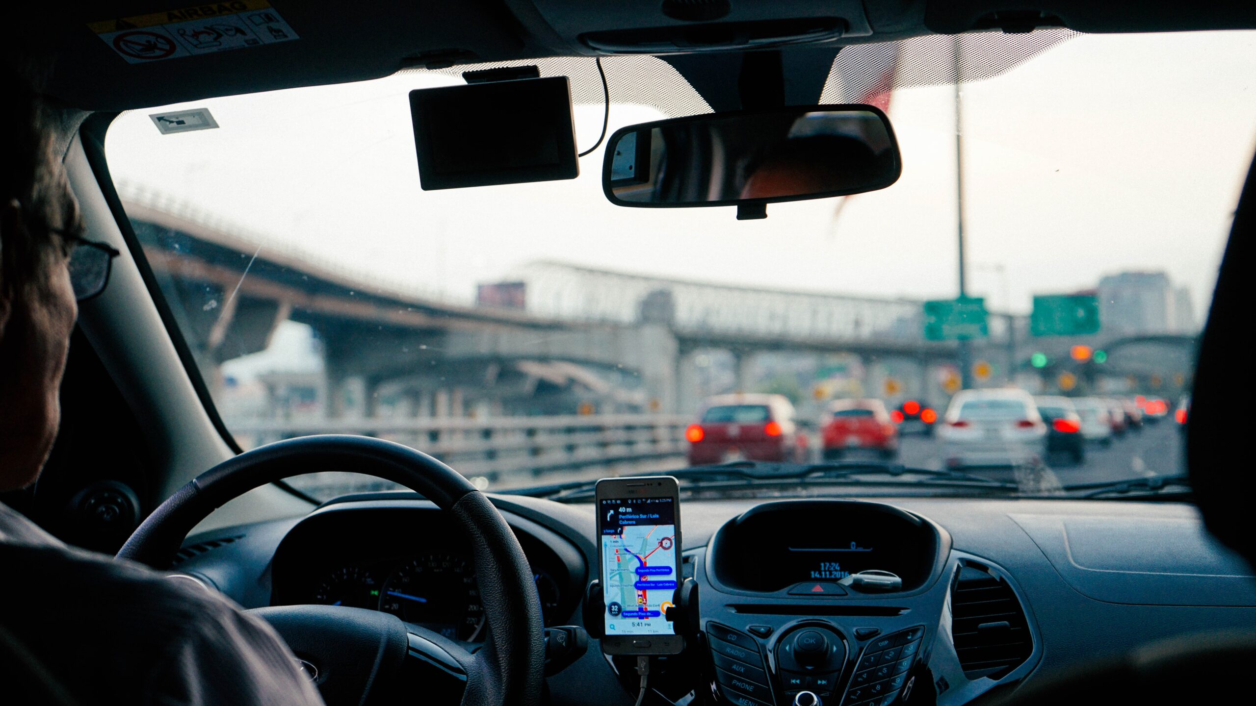 View from the passenger seat of a driver on a busy road, with a phone showing navigation