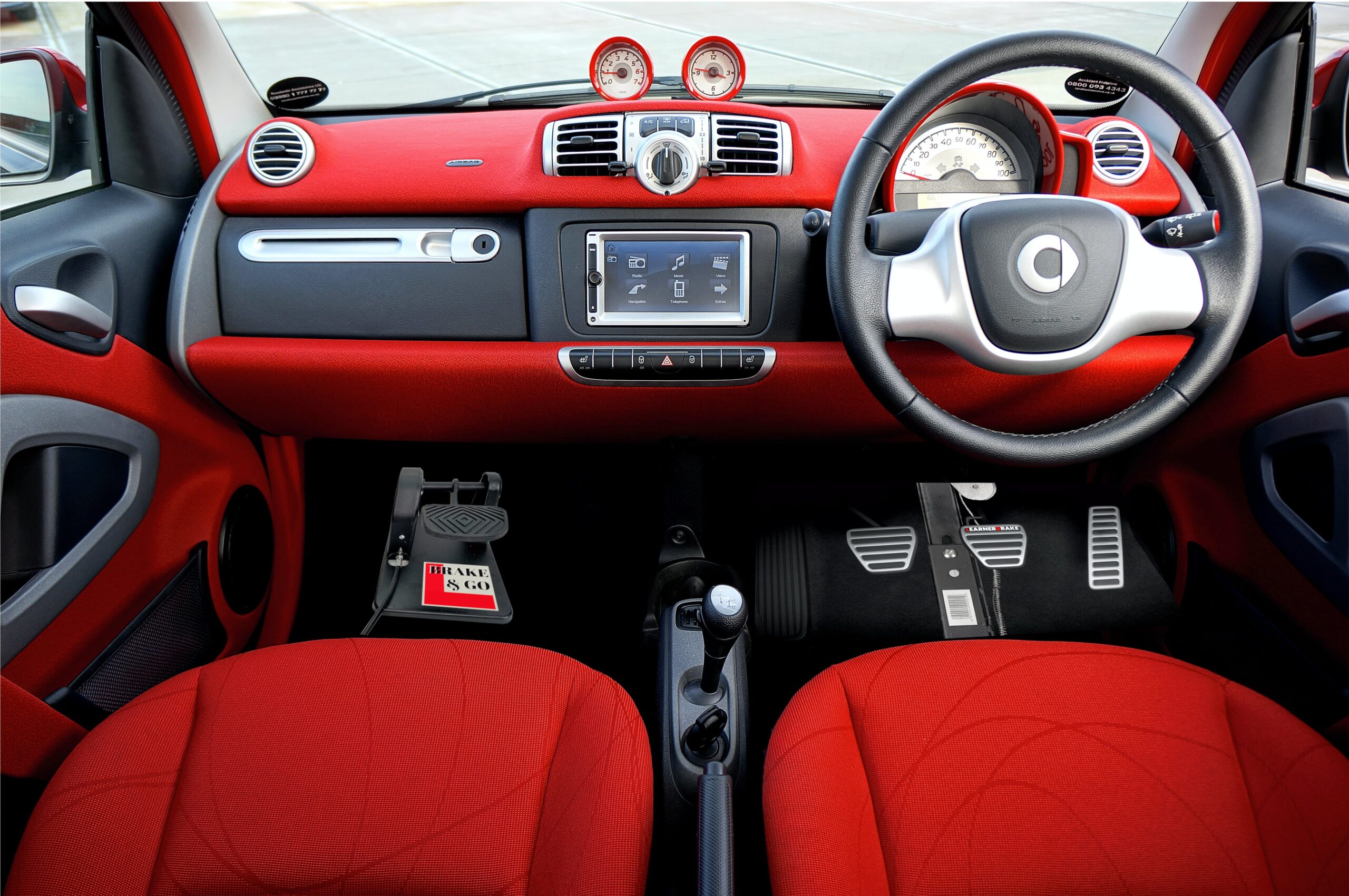 Inside a car with red seats: the LearnerBrake passenger brake pedal fitted in the passenger footwell