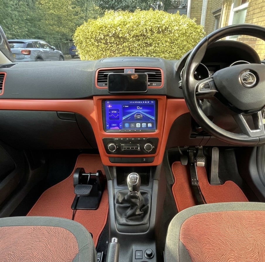 Inside a right-hand-drive car: the LearnerBrake pedal in the passenger footwell, linked to a clamp on the driver's brake pedal